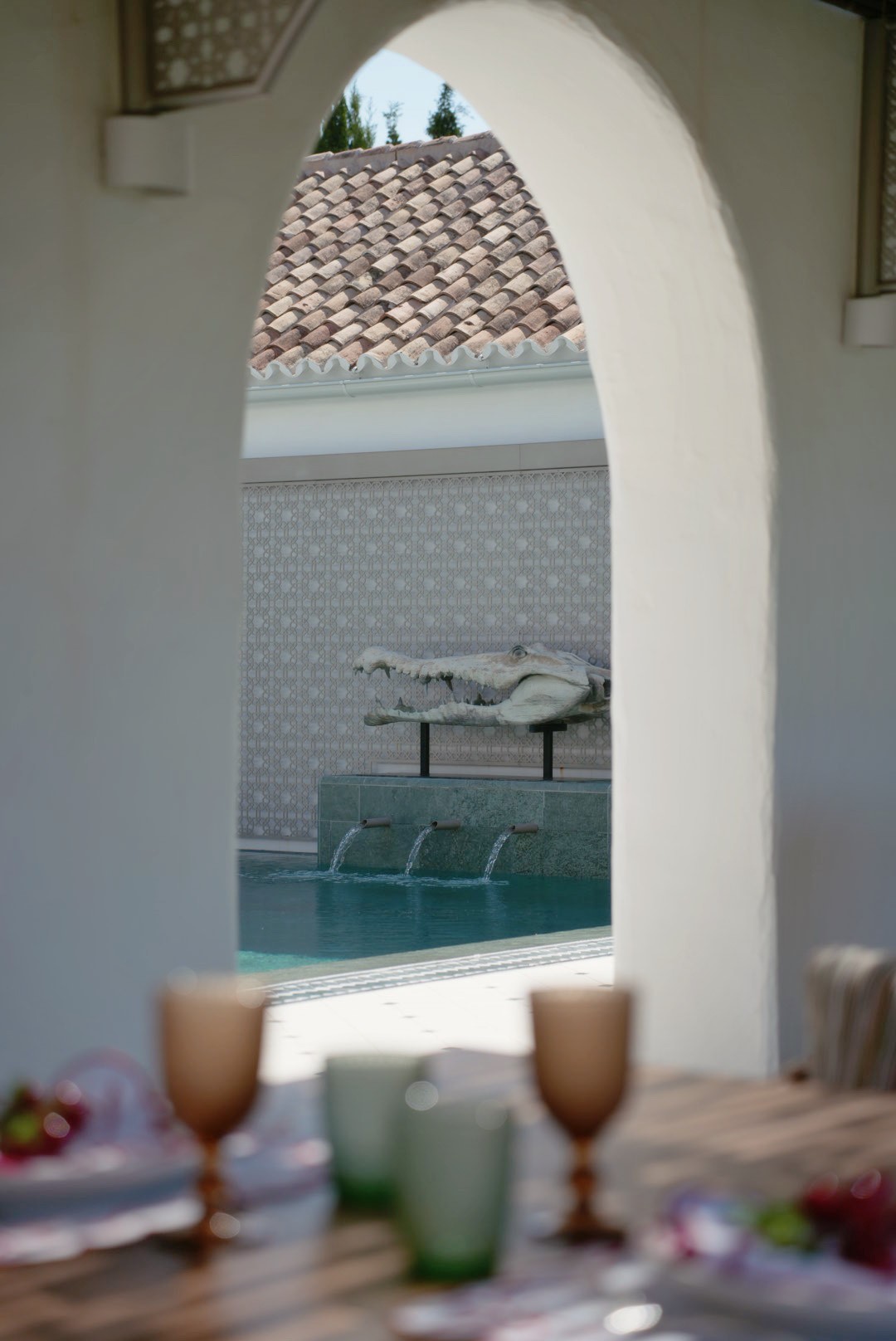 Pool and fountain framed by a stone archway at a dining terrace